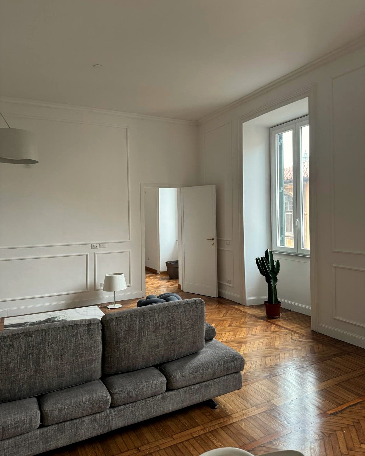 Soggiorno con soffitti alti, boiserie e parquet a spina